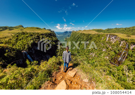 Hiker woman enjoy on cliff and looks at the Espraiado Canyon park in Santa Catarina, Brazil. 108054414