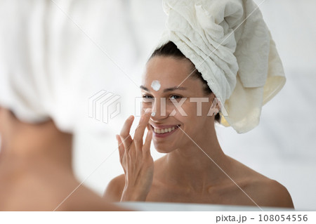 Smiling girl use nourishing face cream in bath Smiling girl use nourishing face cream in bath 108054556