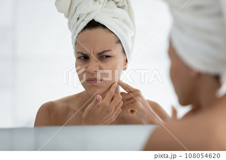 Unhappy young woman squeeze pimple in bathroom 108054620