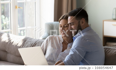 Happy married couple resting on sofa with gadget Happy married couple resting on sofa with gadget 108054647