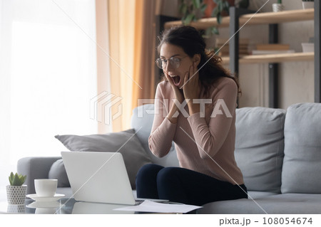 Surprised excited woman wearing glasses looking at laptop screen 108054674