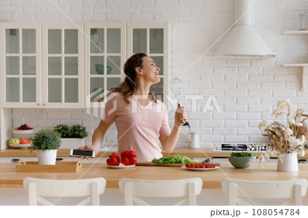 Happy chef girl having fun in kitchen, cooking healthy food Happy chef girl having fun in kitchen, cooking healthy food 108054784