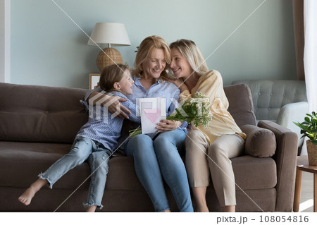 Excited happy girl and young mom congratulating grandma on birthday Excited happy girl and young mom congratulating grandma on birthday 108054816