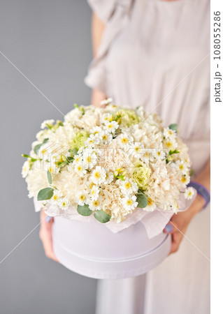 Flower arrangement in round box. Beautiful bouquet of mixed flowers in woman hand. Floral shop concept . Handsome fresh bouquet. Flowers delivery Flower arrangement in round box. Beautiful bouquet of mixed flowers in woman hand. Floral shop concept . Handsome fresh bouquet. Flowers delivery 108055286