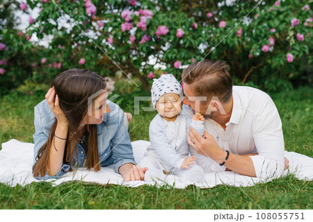 Happy family with young millennial parents and a young son sitting on a picnic blanket and having fun together is a family concept of outdoor lifestyle Happy family with young millennial parents and a young son sitting on a picnic blanket and having fun together is a family concept of outdoor lifestyle 108055751