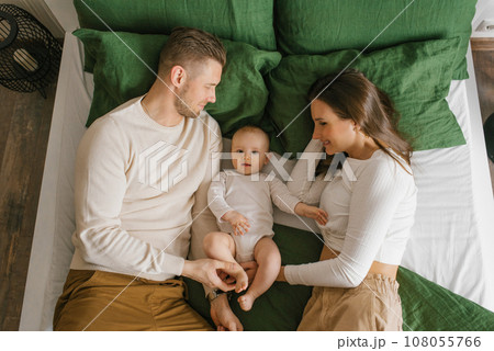 Young happy parents are lying on the bed with their baby son 108055766