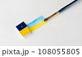 Cuvettes with blue and yellow paint with strips of paint and a brush on a white background place for inscription 108055805