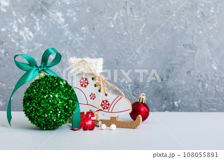Christmas ball with skates on colored background. decoration bauble with ribbon bow with copy space Christmas ball with skates on colored background. decoration bauble with ribbon bow with copy space 108055891