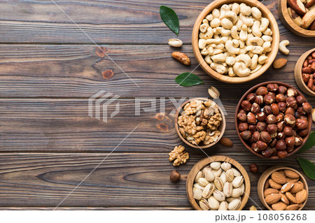 mixed nuts in wooden bowl. Mix of various nuts on colored background. pistachios, cashews, walnuts, hazelnuts, peanuts and brazil nuts 108056268
