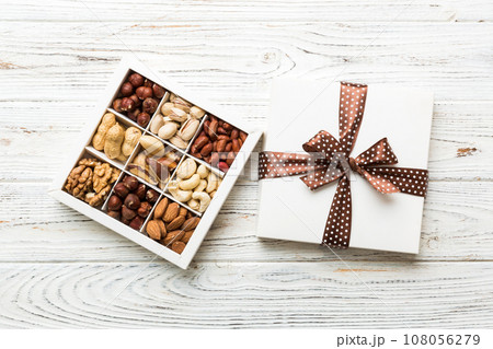 Various varieties of nuts lying in paper box on table background. Top view. Healthy food. Close up, copy space, top view, flat lay. Walnut, pistachios, almonds, hazelnuts and cashews Various varieties of nuts lying in paper box on table background. Top view. Healthy food. Close up, copy space, top view, flat lay. Walnut, pistachios, almonds, hazelnuts and cashews 108056279