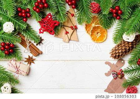 Top view of fir tree branches and festive decorative toys on wooden background. New Year time concept with empty space for your design Top view of fir tree branches and festive decorative toys on wooden background. New Year time concept with empty space for your design 108056303