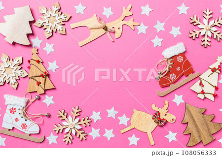 Top view of pink background decorated with festive toys and Christmas symbols reindeers and New Year trees. Holiday concept with copy space 108056333