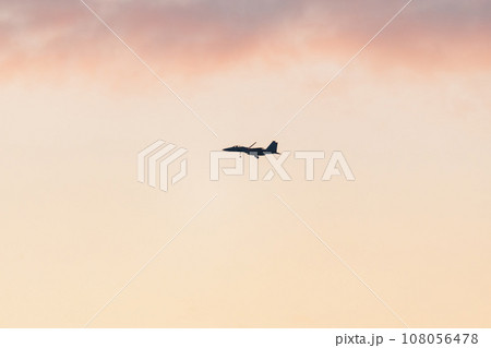美しい夕空を滑空する戦闘機 108056478