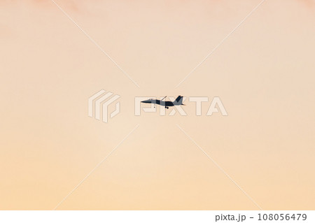 美しい夕空を滑空する戦闘機 108056479