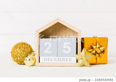 25 december. Christmas composition on colored background with a wooden calendar, with a gift box, toys, bauble copy space 108056998