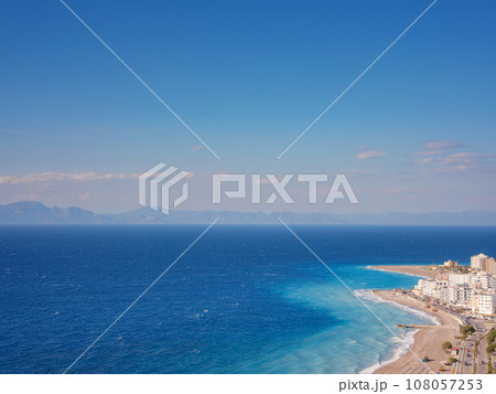 Travel to Greece, Mediterranean islands Rhodes. Aegean beach with sunshades in city of Rhodes view above Travel to Greece, Mediterranean islands Rhodes. Aegean beach with sunshades in city of Rhodes view above 108057253