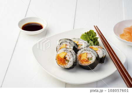 Maki sushi on white plate.Japanese sushi rolls with salmon, cucumber, shrimp eggs and Imitation Crab Stick with soy sauce dip and chopsticks on white wood background. 108057601