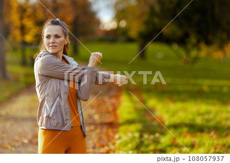 stylish woman in fitness clothes in park stretching 108057937