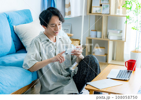 リビングでスマホを使う男性 リビングでスマホを使う男性 108058750