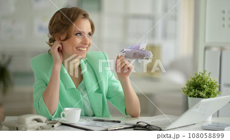 Smiling young businesswoman holding banknotes 108058899