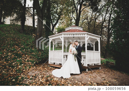 Newly married couple running and jumping in park while holding hands Newly married couple running and jumping in park while holding hands 108059656