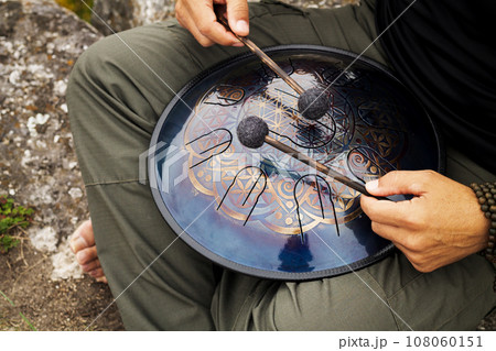 Musician drum sticks playing hand pan percussion instrument 108060151