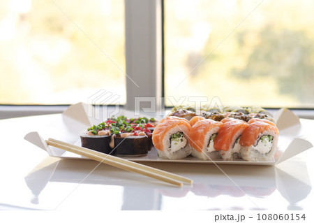 Sushi rolls in disposable paper box on table 108060154