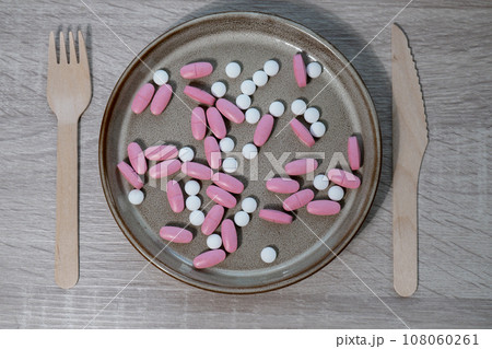 Organizer weekly shots with fork and knife medical pill box with doses of tablets for daily take medicine with white pink drugs and capsules. Daily vitamins at home. Health care and diseases cure 108060261