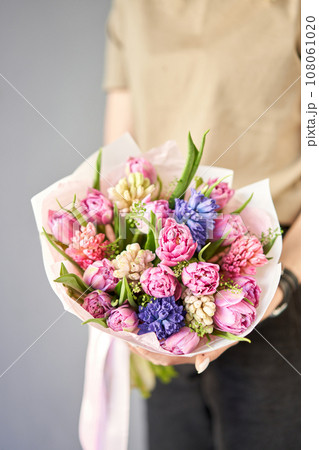 Sunny spring morning. Young happy woman holding a beautiful bunch of hyacinths and tulips in her hands. Present for a smiles girl. Flowers bouquet Sunny spring morning. Young happy woman holding a beautiful bunch of hyacinths and tulips in her hands. Present for a smiles girl. Flowers bouquet 108061020