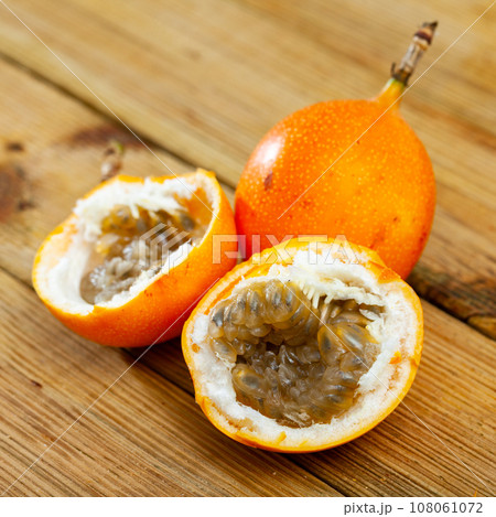 Fresh sweet granadilla whole and halves on wooden table Fresh sweet granadilla whole and halves on wooden table 108061072