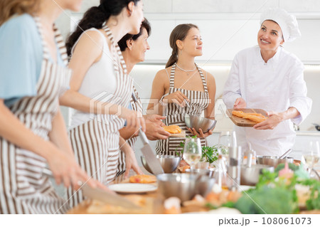 Girl chef tell group of students listeners cooking courses about secrets of cooking juicy chicken Girl chef tell group of students listeners cooking courses about secrets of cooking juicy chicken 108061073
