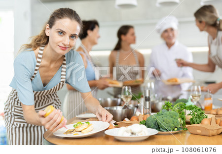 Young woman decorating cooked chicken breast with mustard 108061076