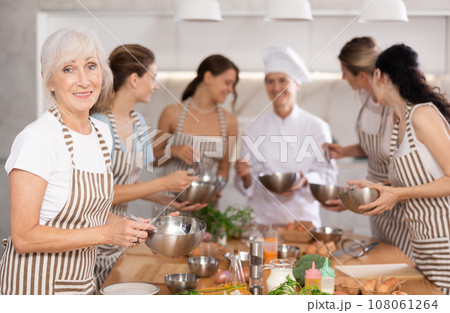Lady while studying at culinary workshop, cooks appetizing sauce, marinade, dough in bowl. Lady while studying at culinary workshop, cooks appetizing sauce, marinade, dough in bowl. 108061264