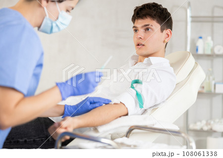 Young man having vein injection lying on clinical chair 108061338