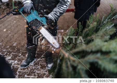 Man cuts a part of the trunk from a Christmas tree with a chainsaw 108063740