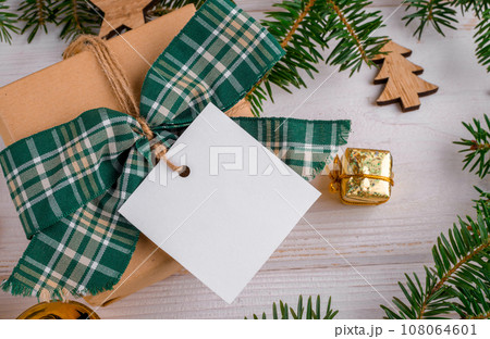 Christmas square gift tag mockup with craft wrapped gift box and fir branches around, close up 108064601