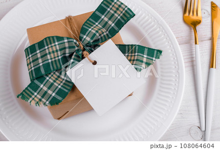 Christmas square gift tag mockup with craft wrapped gift box on a white plate, close up 108064604