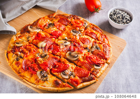 American St. Louis Style pizza with bacon, mushrooms and tomatoes on a board 108064648