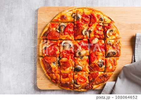 Close up of St. Louis Style pizza with bacon, mushrooms, tomatoes and peppers on a board top view 108064652