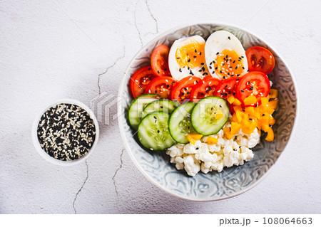 Close up of cottage cheese bowl with tomatoes, cucumber, pepper and egg on the table top view 108064663