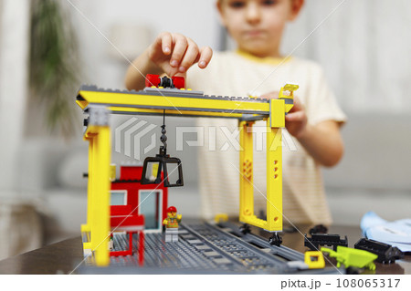 Child boy playing and building with colorful plastic bricks at the table Child boy playing and building with colorful plastic bricks at the table 108065317