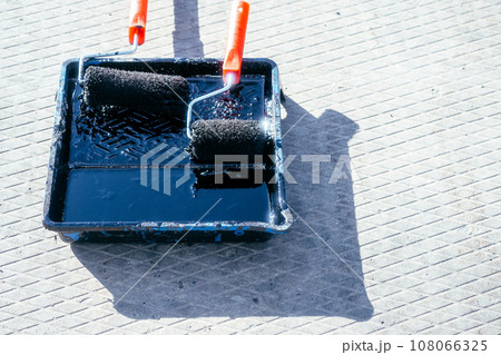 Paint roller in tray with black industrial paint or primer. Top view of paint roller with paint tray 108066325