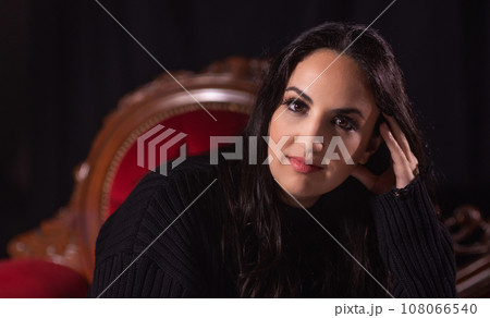 Young woman with a confident look sitting on a couch Young woman with a confident look sitting on a couch 108066540