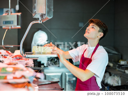Young man weighing cheese at counter Young man weighing cheese at counter 108073510