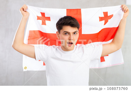 Male football fan holding Georgia flag Male football fan holding Georgia flag 108073760