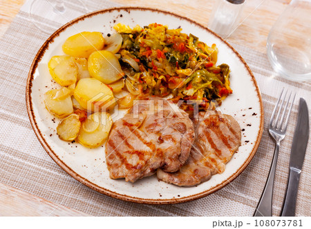 Roasted pork steak with baked potatoes and stewed cabbage Roasted pork steak with baked potatoes and stewed cabbage 108073781