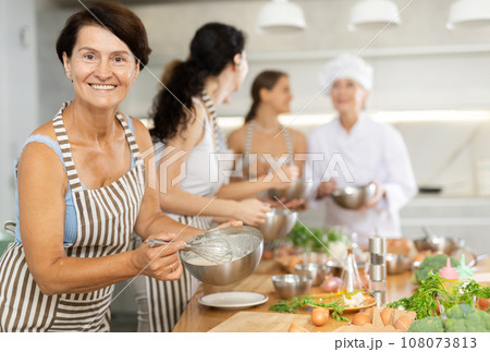 Lady while studying at culinary workshop, cooks appetizing sauce, marinade, dough in bowl. 108073813