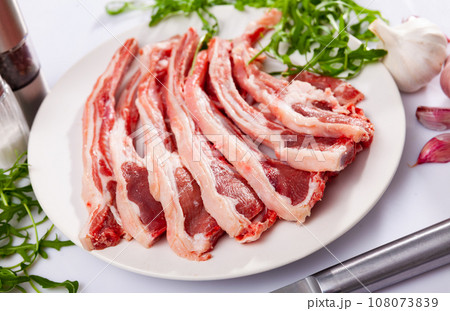 Fresh uncooked lamb chops on plate, over white background Fresh uncooked lamb chops on plate, over white background 108073839