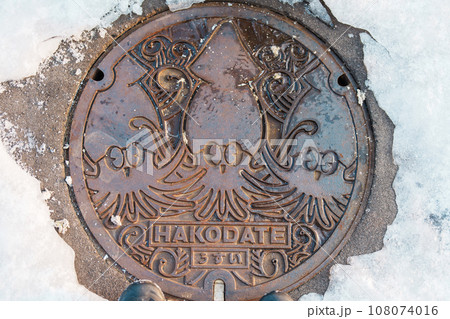 Hakodate city manhole cover with snow in winter season. Hakodate in one of landmark and popular for tourists attractions in Hokkaido, Japan. Travel and Vacation concept Hakodate city manhole cover with snow in winter season. Hakodate in one of landmark and popular for tourists attractions in Hokkaido, Japan. Travel and Vacation concept 108074016