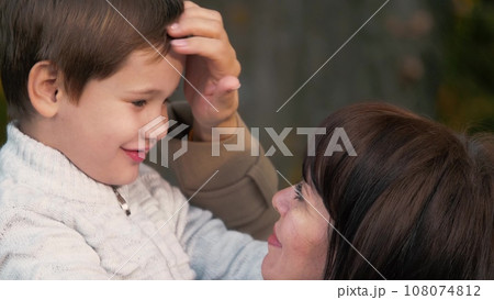 Mother stands holding son in arms. Mother amidst foliage of park holds son creating scene. Mother in lively park holding preschooler son in arms shares special moment underscoring beauty of season Mother stands holding son in arms. Mother amidst foliage of park holds son creating scene. Mother in lively park holding preschooler son in arms shares special moment underscoring beauty of season 108074812